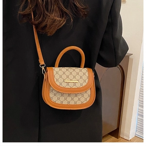 Detail of vintage saddle bag with monogram pattern and gold metal hardware on black blazer