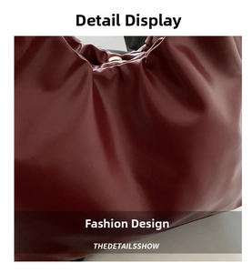 Detail view of burgundy ruched faux leather handbag with elegant gold metal ring clasp