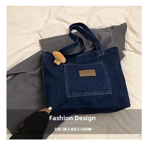 Close-up of deep blue denim tote bag with leather logo and yellow mushroom pendant