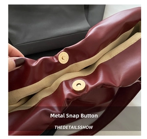 Close-up of golden magnetic hardware closure on burgundy leather tote bag detail