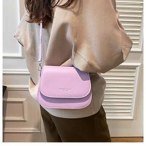 Lilac crossbody bag with curved flap and adjustable strap shown on model outdoors