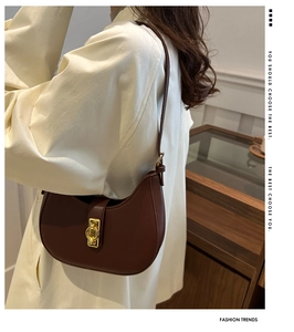 Detail view of a vintage dark brown half-moon underarm bag with gold metal buckle