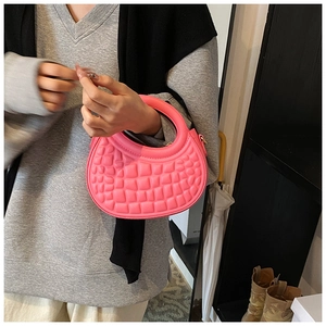 Detail of pink crescent handbag with textured faux leather finish and top handle