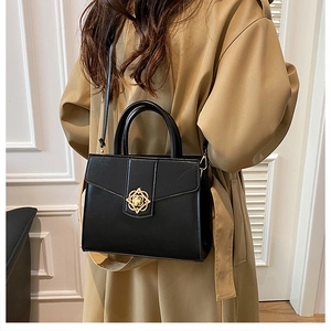 Détail du sac en similicuir noir avec fermoir fleur dorée et tenue avec manteau camel