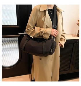 Close-up of black crossbody bag with adjustable wide strap and buckles in a lifestyle setting