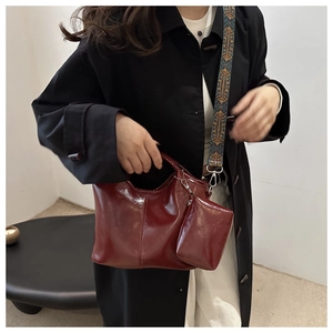 Dettaglio della borsa a secchiello bordeaux con tracolla in tessuto stile etnico