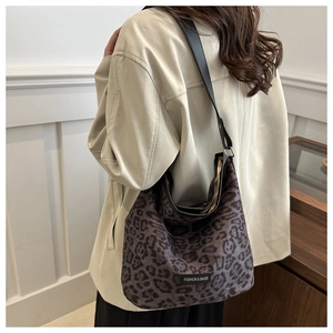 Detail of leopard print suede shoulder bag featuring a leather logo tag and black strap