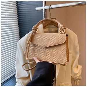 Detail of light beige crossbody bag featuring textured weave and a stylish knotted handle
