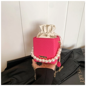 Detail of rose pink woven bucket bag with pearl handle and golden chain strap