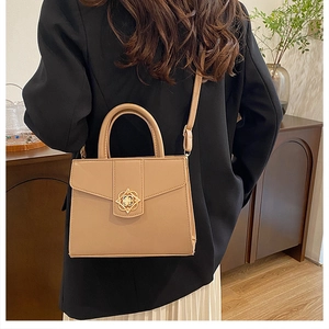 Mannequin portant un sac bandoulière beige chic avec boucle dorée sur blazer noir et robe blanche