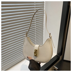 Dettaglio della borsa a mezzaluna color crema con elegante fibbia circolare dorata