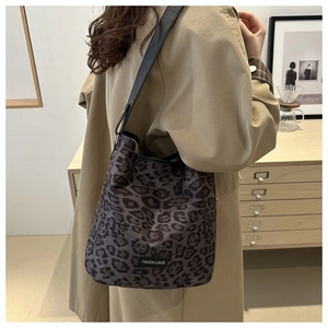Detail of leopard print hobo bag with black strap worn by a model in a modern room