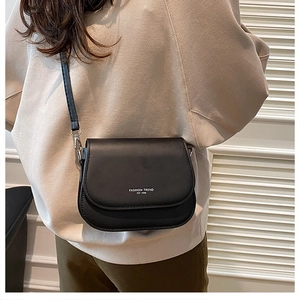 Detailed view of black saddle bag with FASHION TREND print on stylish female model