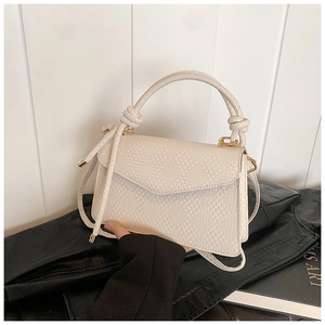 Detail of cream white woven PU leather handbag with a knotted handle and gold metal hardware