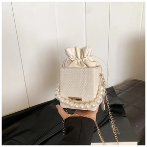 Detailed view of woven texture bucket bag with large pearl handle and golden chain