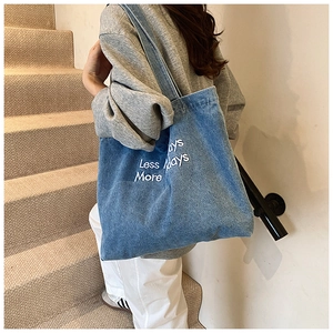 Blue denim tote bag with Less Days More Days embroidery shown from a frontal perspective
