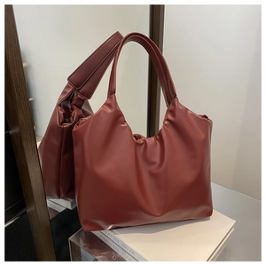 Detail view of burgundy leather tote bag with pleated design and wide shoulder strap
