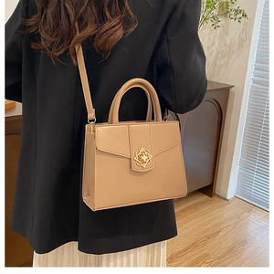 Détail du sac à main beige minimaliste avec fermoir fleur dorée porté par un mannequin