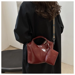 Model wearing a deep red glossy oil wax leather tote bag with jacquard shoulder strap