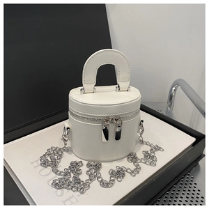Detailed macro of white mini bucket bag with dual zippers and silver chain on books