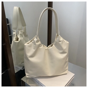 Detail of minimalist cream tote bag with pleat design and soft leather texture on mirror