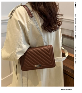 Brown quilted crossbody bag with silver chain strap worn with a beige trench coat