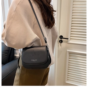 Detail of black matte saddle bag with silver brand logo and adjustable strap