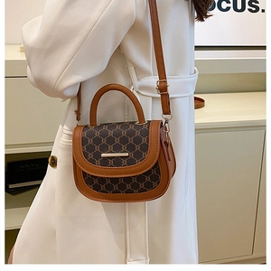 Detail of vintage saddle bag featuring monogram canvas with tan leather trim and top handle