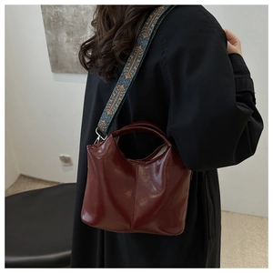 Detail of burgundy oil wax leather tote bag with a colorful jacquard shoulder strap