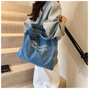 Détail d'un sac en denim bleu avec broderie blanche Less Mondays More Sundays