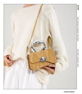 Detail of yellow pleated handbag with liquid-style silver metal handle and modern clasp