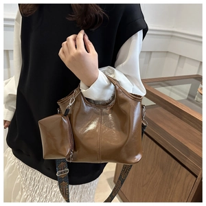 Detail of caramel oil wax tote with patterned wide strap and small round charm pouch