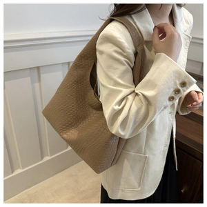 Detail of dark khaki woven tote bag showing side profile and wide shoulder strap texture
