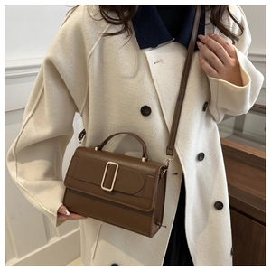 Deep brown crossbody bag with gold buckle shown on a model wearing a beige coat
