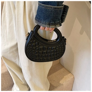 Close-up of black crocodile-embossed PU leather handbag with circular handle and gold hardware