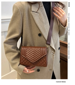 Close-up of brown quilted leather bag with elegant V-shaped stitching and wide strap