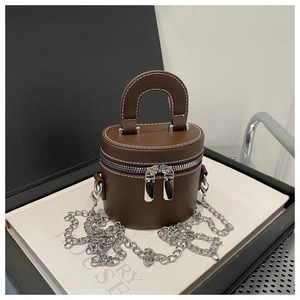 Detail of brown bucket bag with dual zippers, white stitching, and silver chain strap