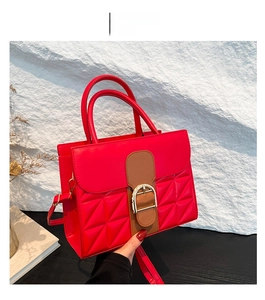 Détail du sac rouge matelassé à motif crocodile avec boucle fer à cheval dorée et poignée