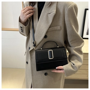Close-up of a black matte leather crossbody bag with an elegant golden metal buckle