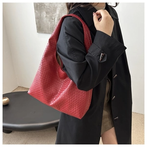 Détail du tissage rouge d'un sac cabas hobo porté sur un manteau noir élégant