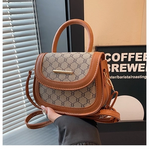 Detailed close-up of a brown patchwork saddle bag with gold metal trim and leather handle