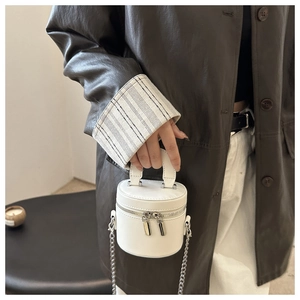 Detailed side view of white mini bucket bag with silver chain and double zipper closure