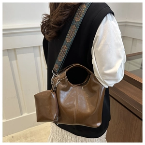 Borsa tote marrone in pelle cerata con tracolla larga geometrica indossata dal modello