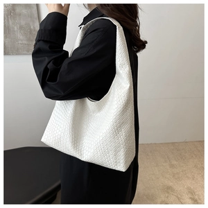Détail du sac hobo blanc tressé montrant la texture précise sur l'épaule de femme