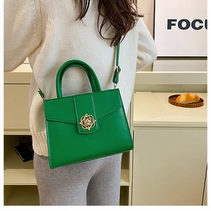 Détail d'un sac à main vert en similicuir avec fermoir fleuri doré et texture