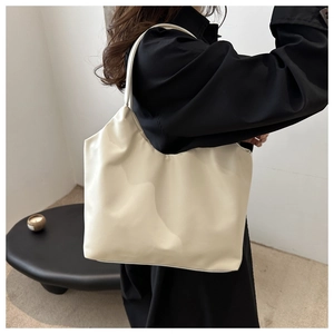 Detail of minimalist cream white tote bag with smooth texture on a model shoulder