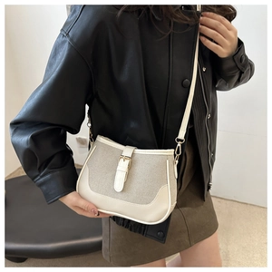 Detail of cream leather and fabric crossbody bag with gold buckle on a model