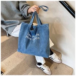 Detail of blue denim tote bag featuring Less Mondays More Sundays white printed text