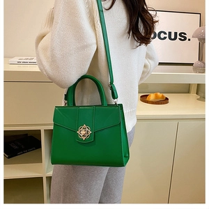 Détail d'un sac à main vert vif structuré avec fermoir floral doré et poignée haute