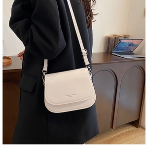 Gros plan du sac à bandoulière crème avec imprimé Fashion Trend sur un blazer noir